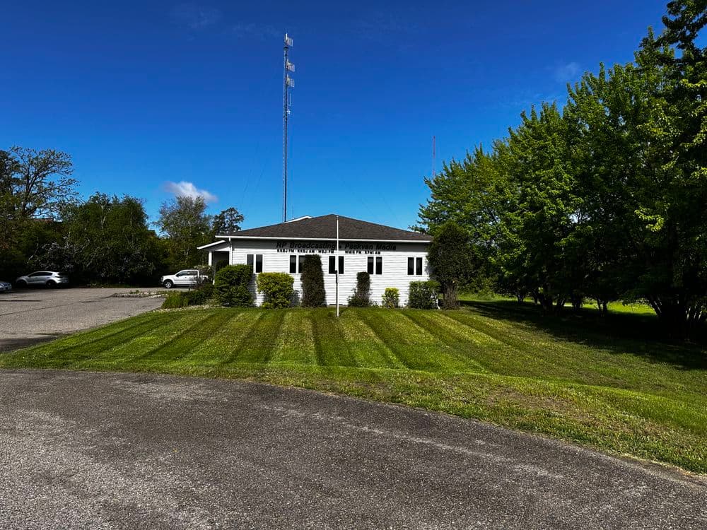 White building with manicured lawn, cell tower in background, clear blue sky.
