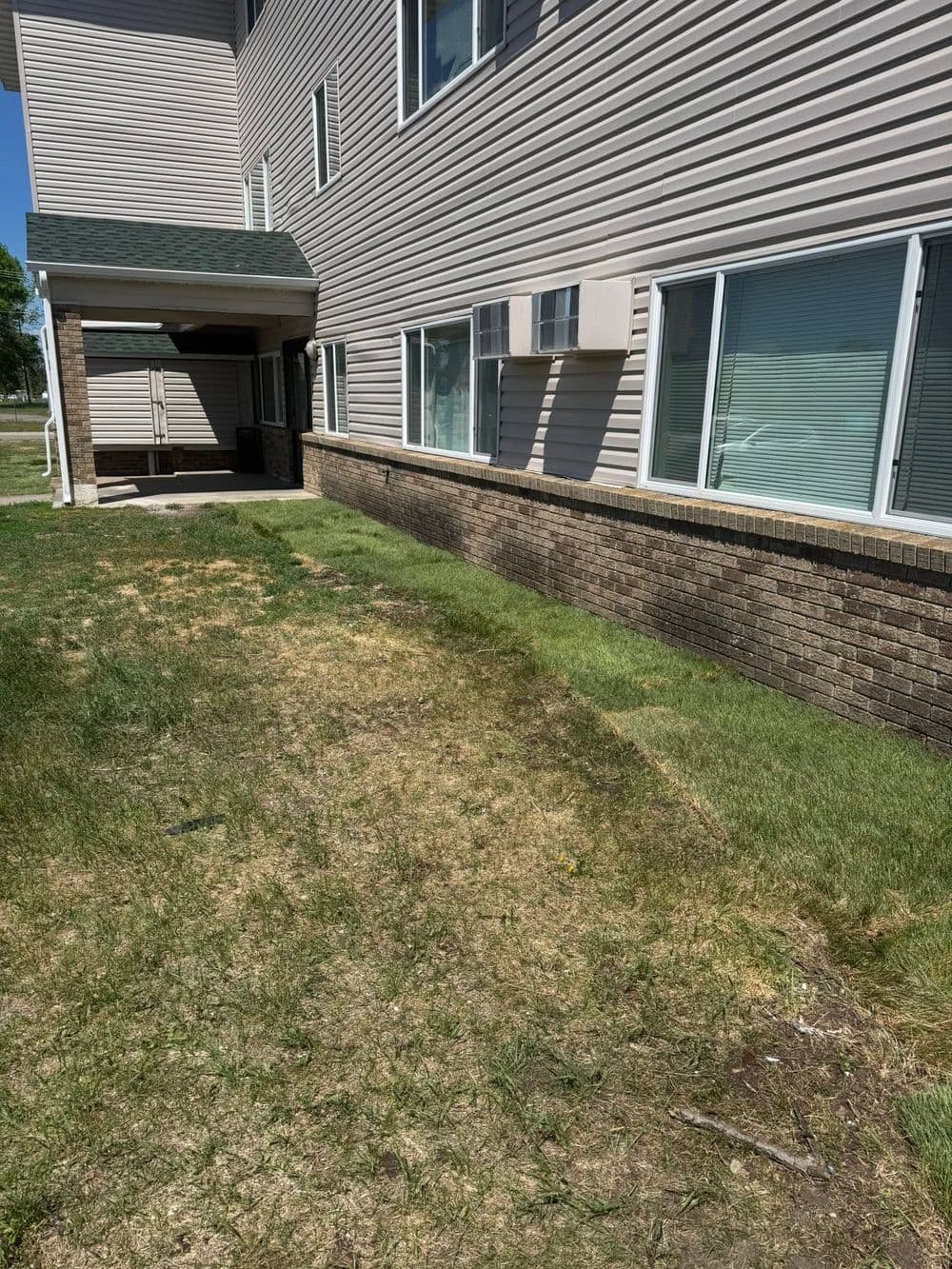 Exterior view of a building with grass, windows, and air conditioning units.